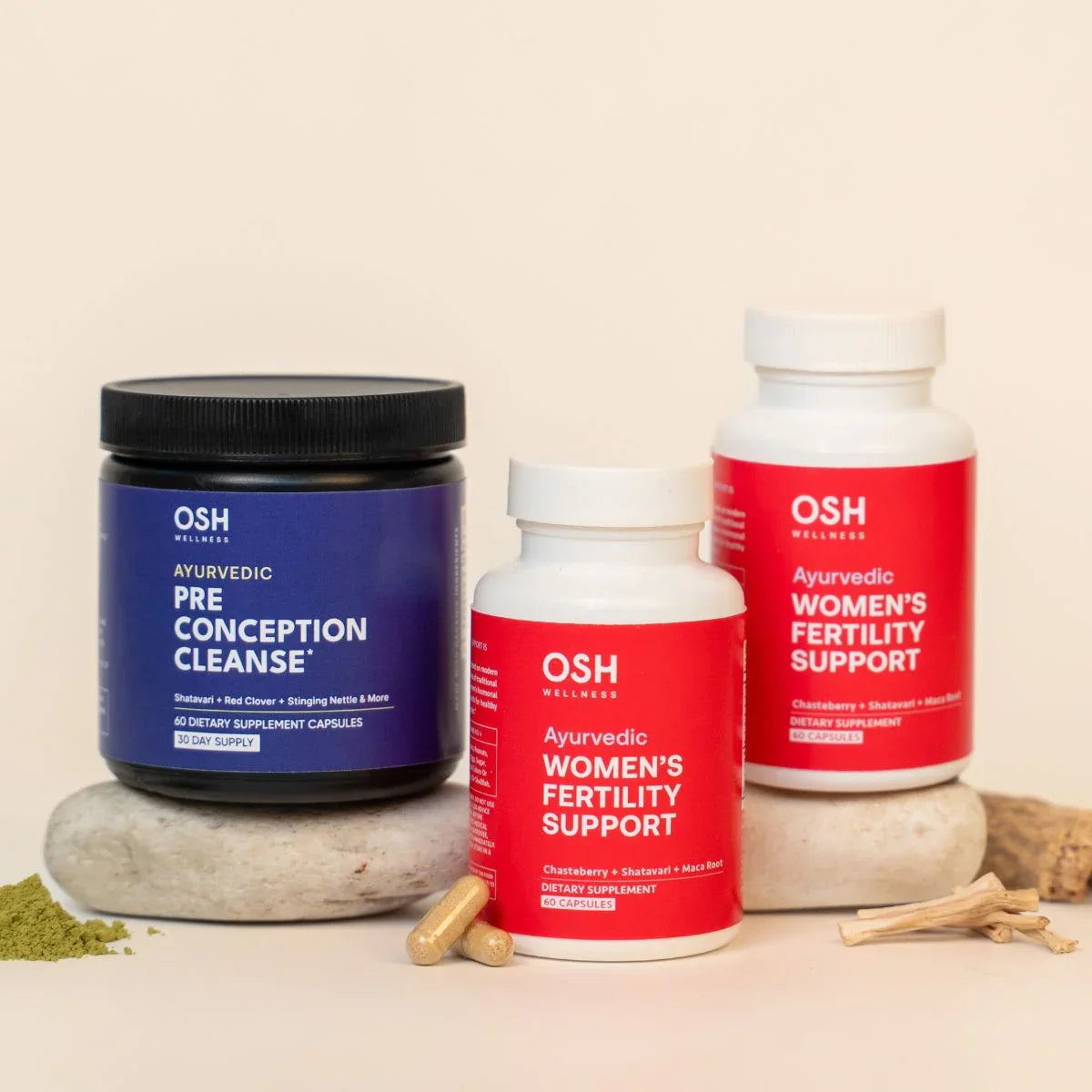 Three bottles of OSH Wellness Ayurvedic supplements, one blue "Pre Conception Cleanse" and two red "Women's Fertility Support," arranged on stones and other natural elements.