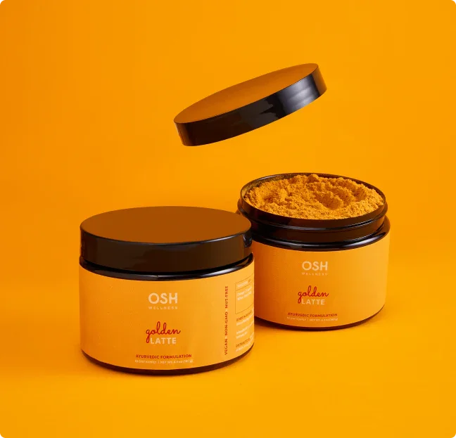 Two jars of golden latte mix with black lids, one open with lid floating.
