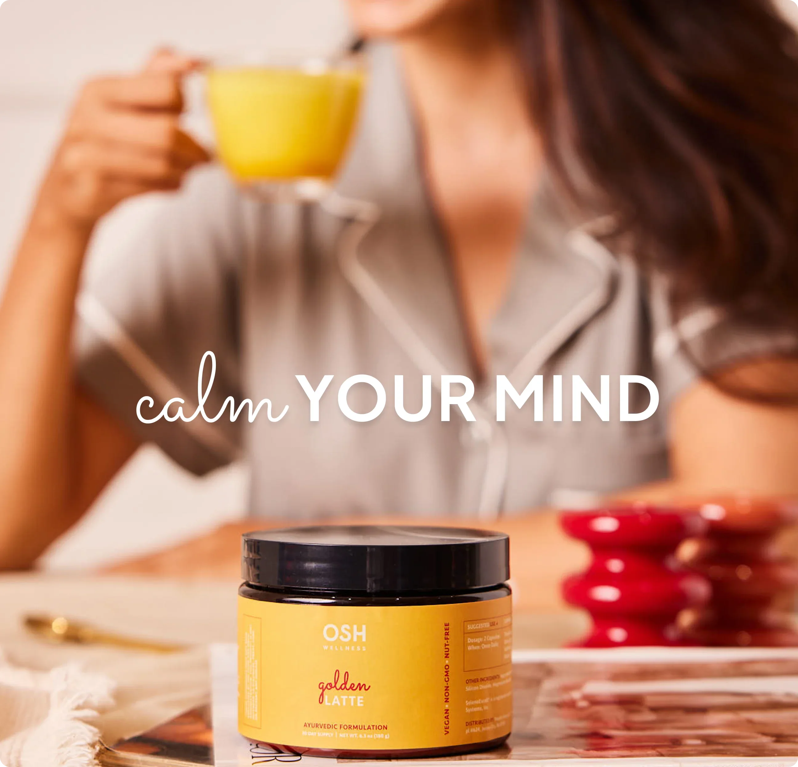 A woman in pajamas holds a yellow drink behind a jar of "OSH golden LATTE".